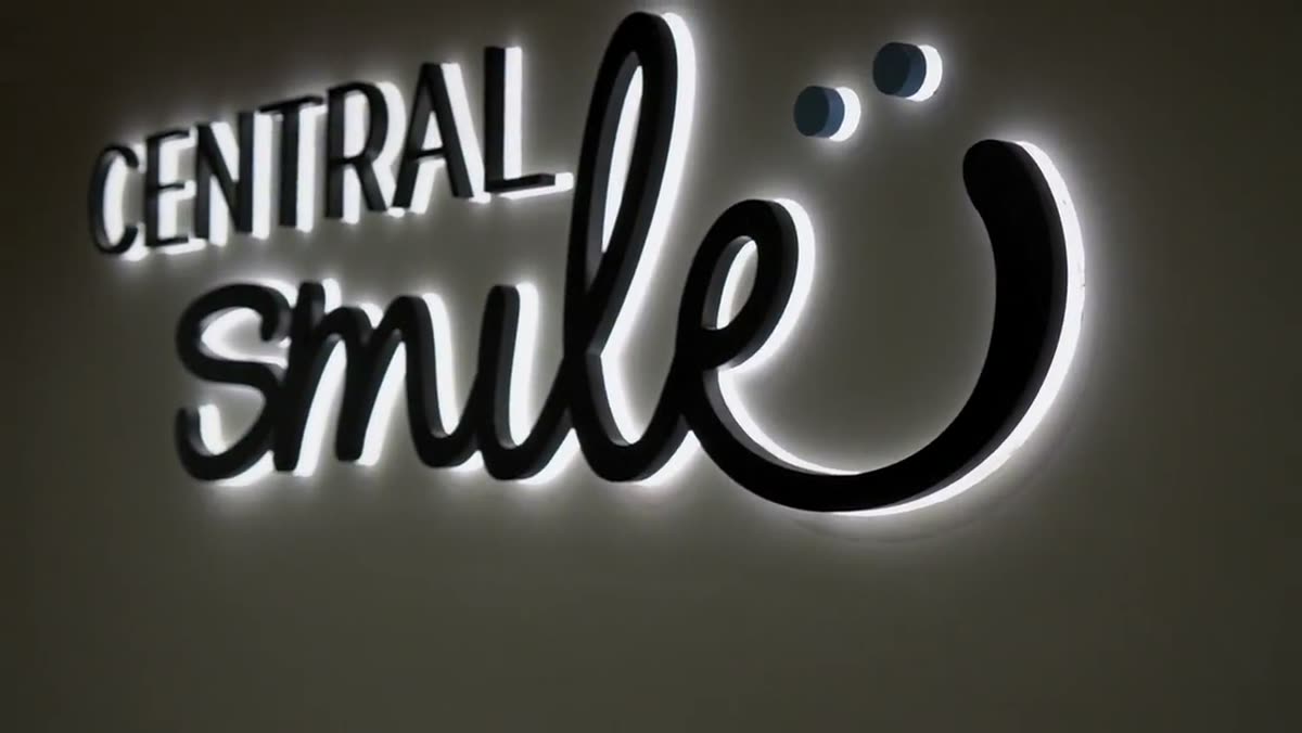 The illuminated Central Smile logo on the practice wall.