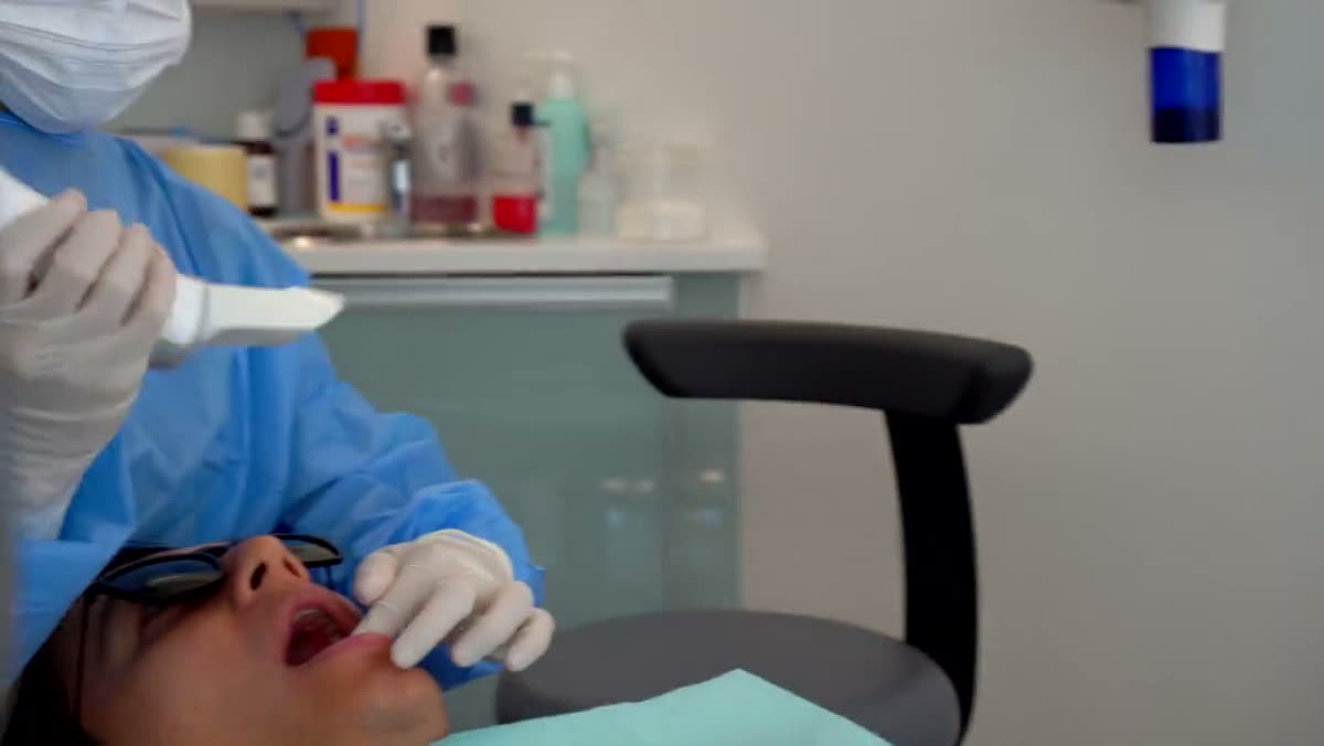A clinician passing an intraoral scanner over a patient in the chair.
