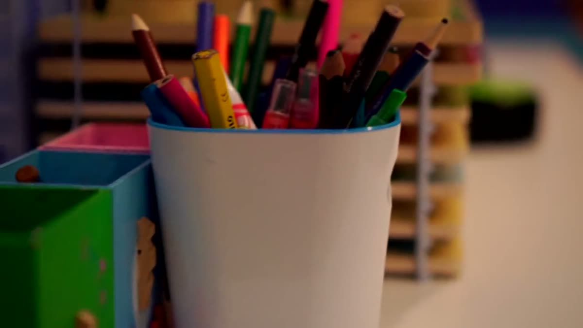 A cup of coloured pencils on a shelf in the practice.