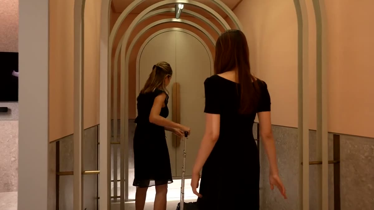 Two women walking through a sequence of arched showroom doorways.