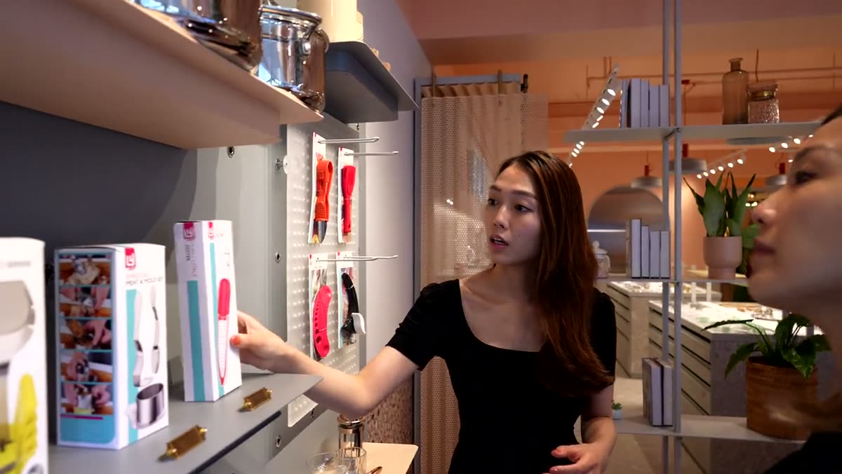 A woman pointing out packaged product on a retail shelf.