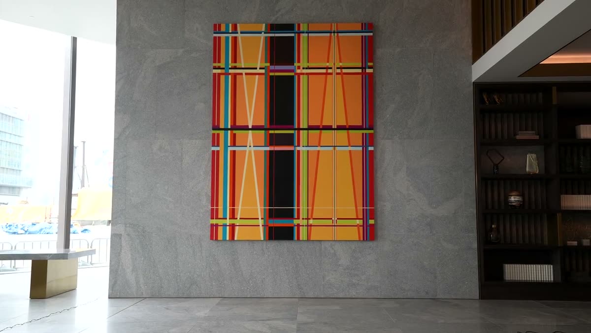 A large geometric line painting hanging on a concrete wall.