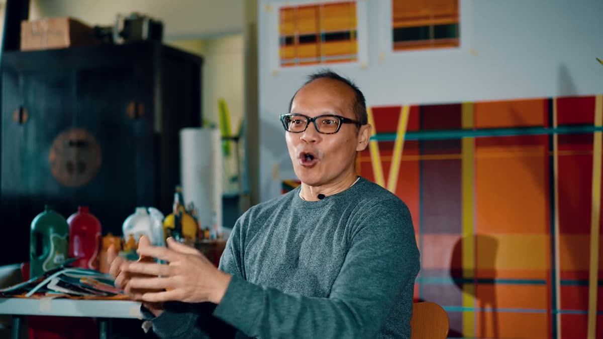 The artist speaking in his studio in front of his work.