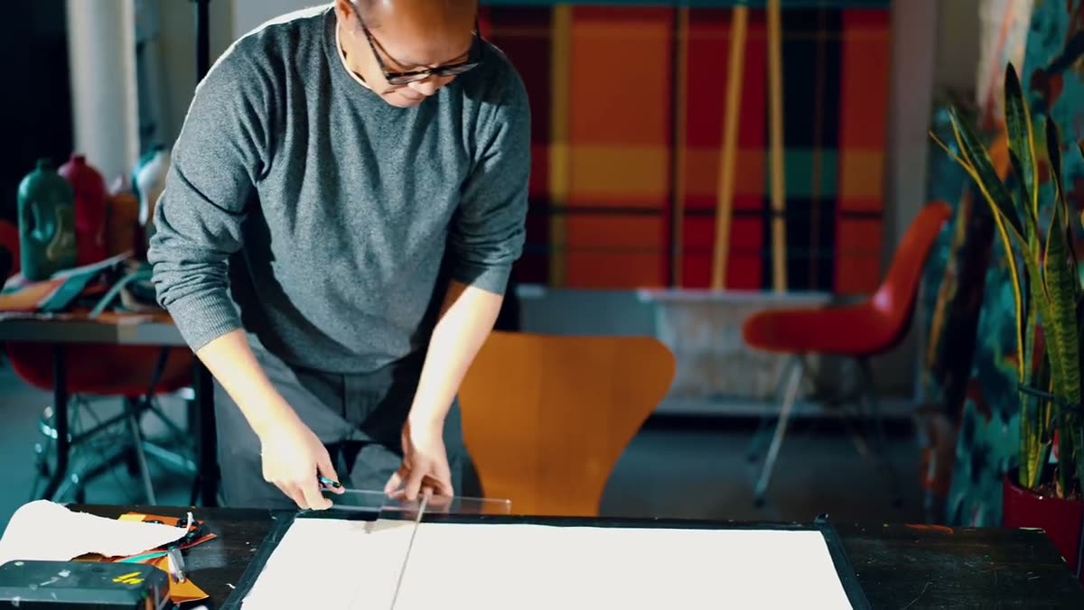 The artist laying masking tape across a fresh white panel.