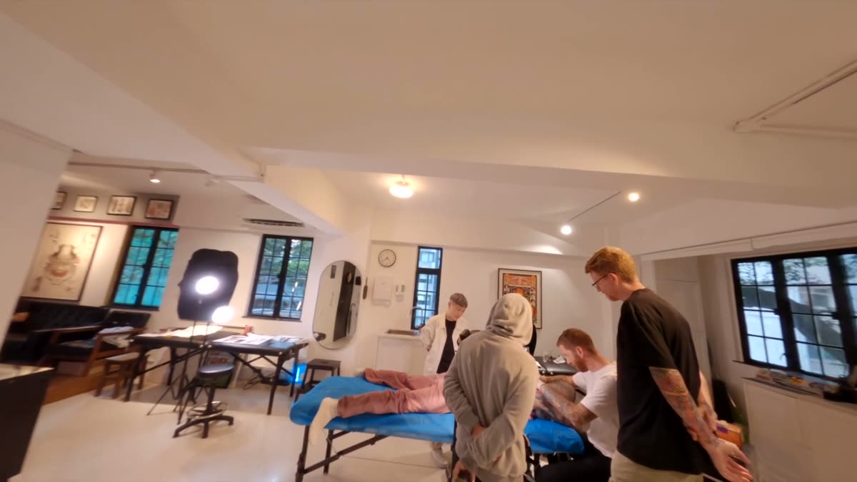A wide interior of the tattoo studio with several artists working.