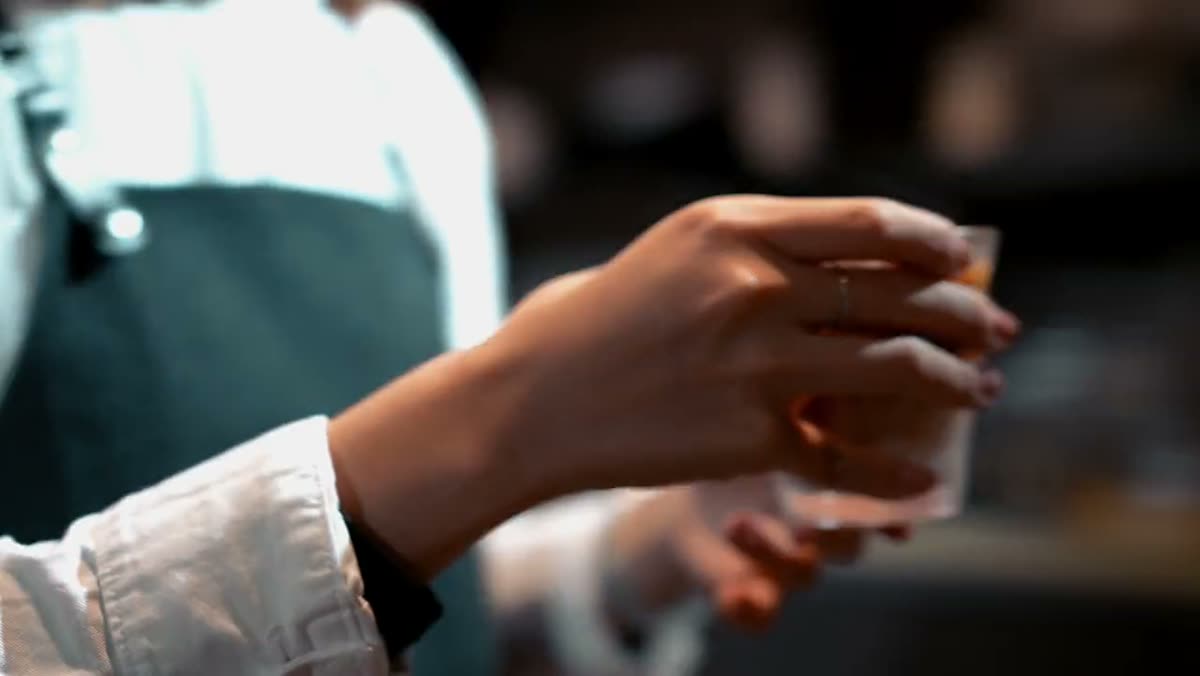 A barista handing a glass across the counter to a customer.