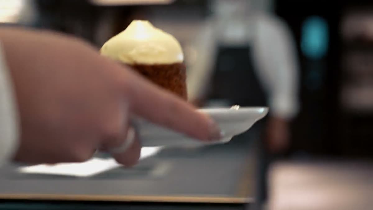 A hand setting a pastry down on a plate.