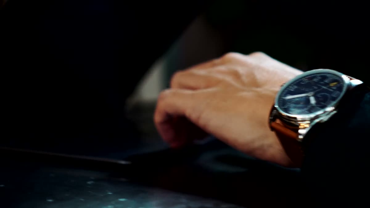A hand resting on a dark surface wearing the watch with a blue dial.