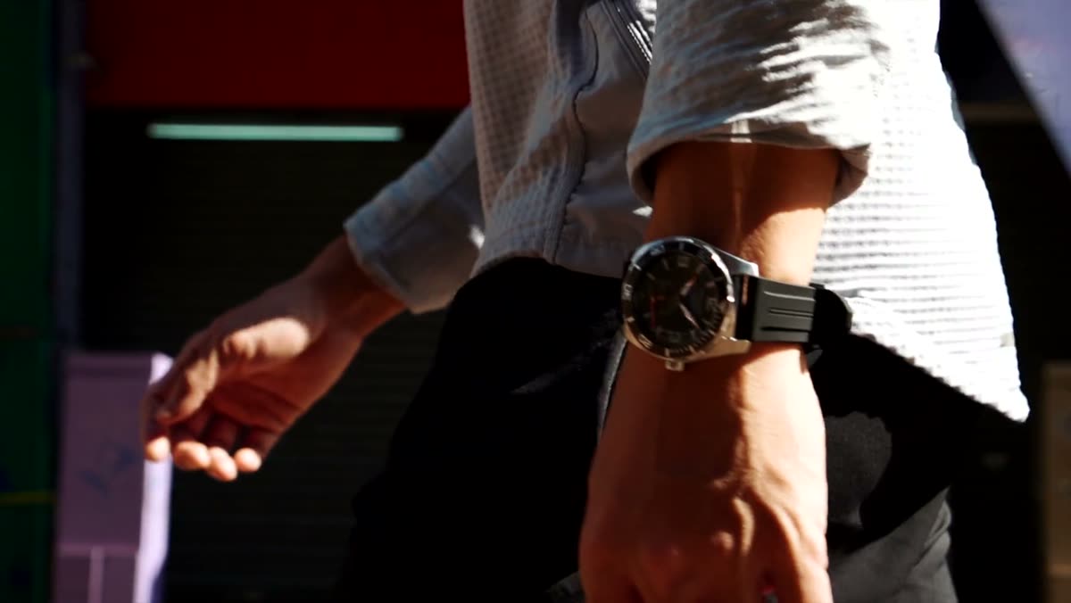A person walking, wearing the watch with a black dial.
