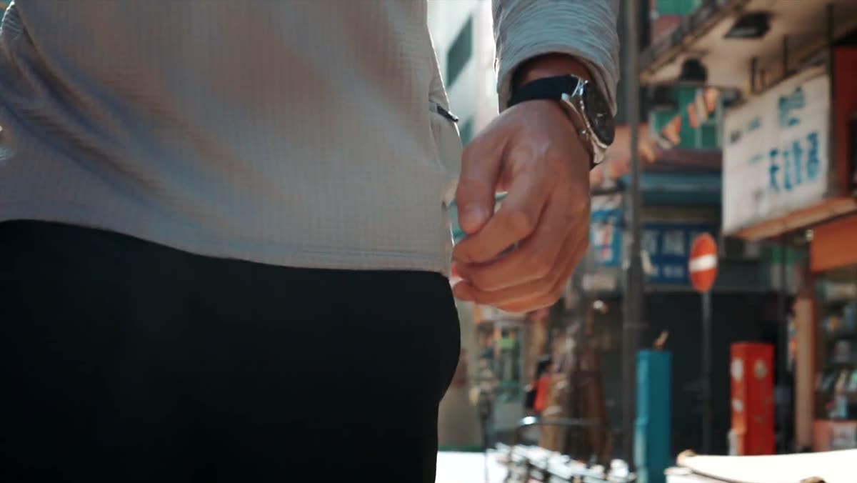 A wrist wearing the watch against a busy street background.