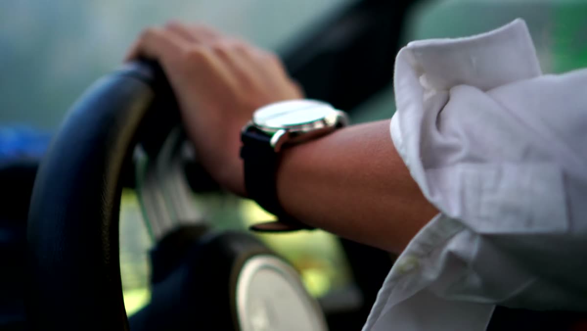 Hands on scooter handlebars, wearing the watch with a white dial.