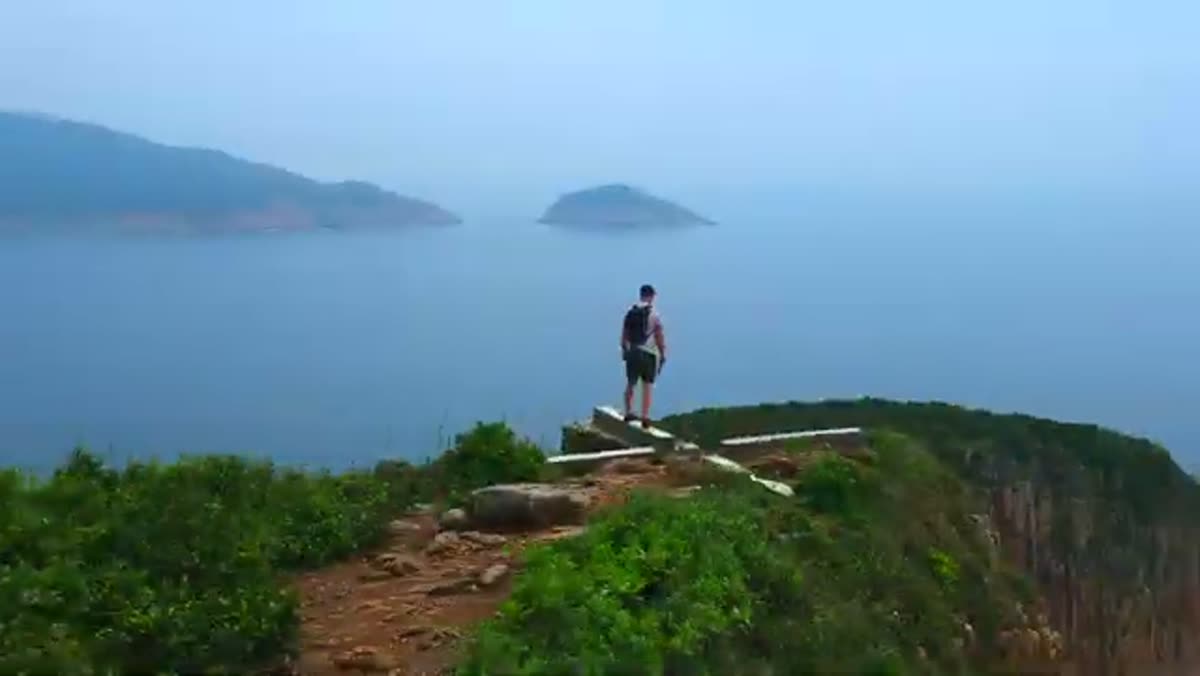 A walker on a ridge above the water.