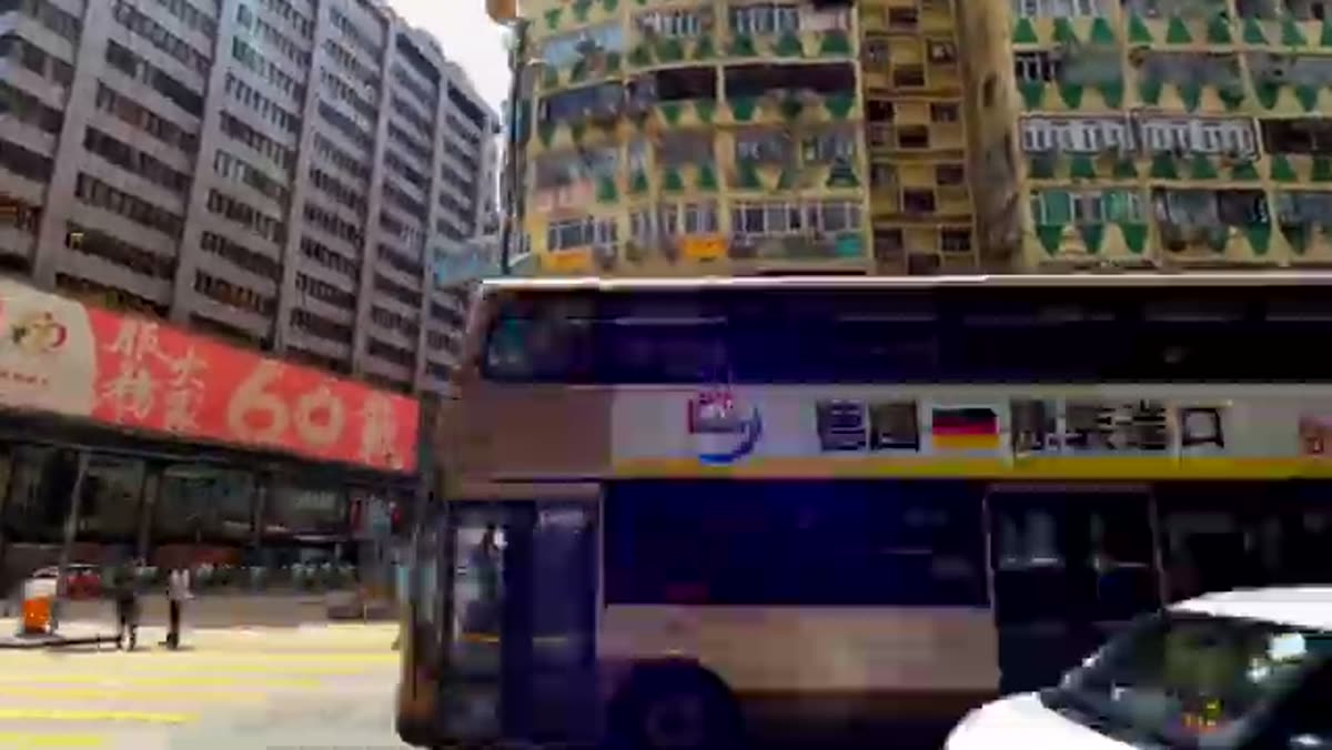 A bus turning under the shop signs.