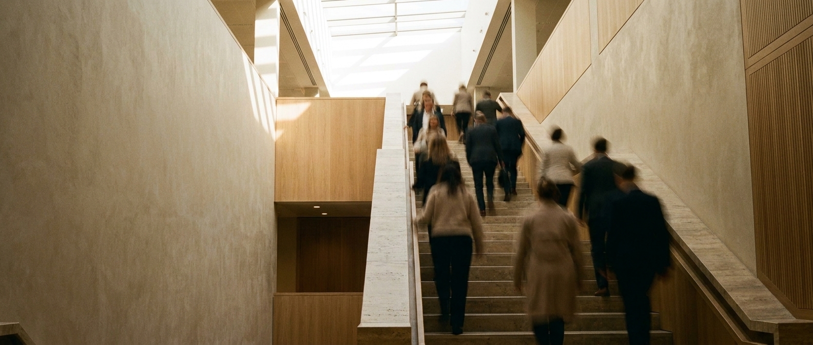 Figures moving up an atrium stair, rendered as motion blur.